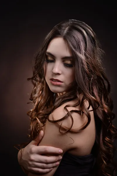 Beautiful young woman with long hair on dark brown background — Stock Photo, Image
