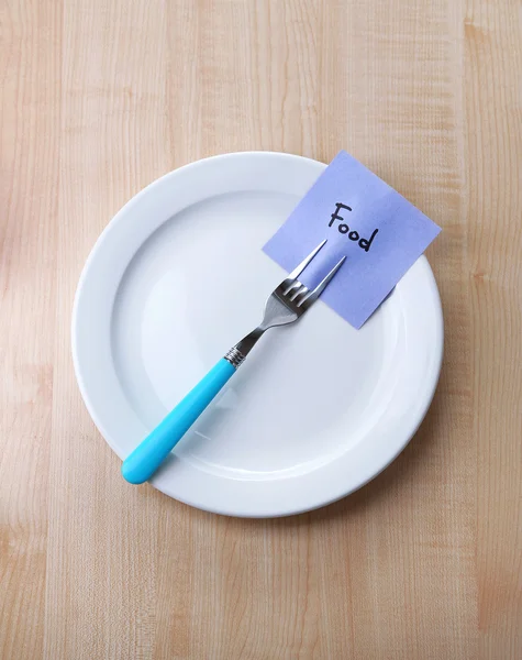Note paper with message  attached to fork, on plate, on color wooden background — Stock Photo, Image