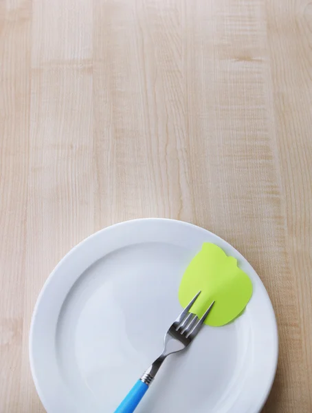 Empty note paper attached to fork, on plate, on color wooden background — Stock Photo, Image