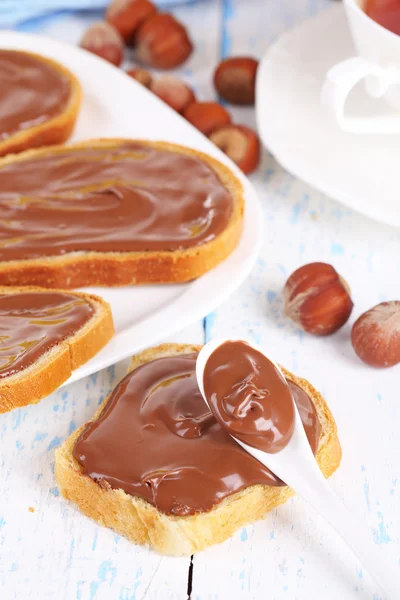 Roti dengan coklat hazelnut manis tersebar di atas piring di atas meja — Stok Foto