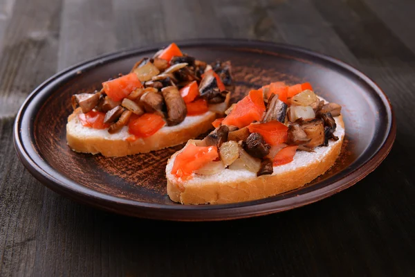 Delicious bruschetta with mushrooms on plate on table close-up — Stock Photo, Image