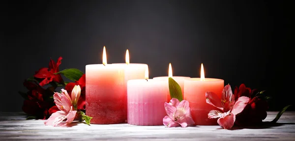 Belas velas com flores na mesa de madeira, no fundo escuro — Fotografia de Stock