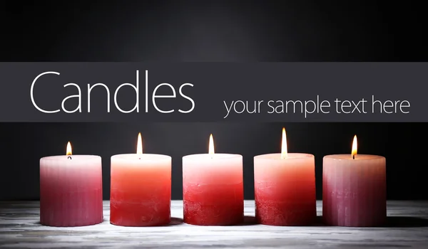Красивые свечи с цветами на деревянном столе, на темном фоне — стоковое фото