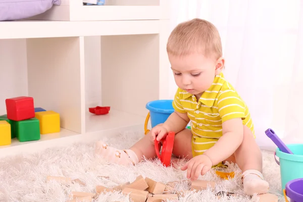 Söt liten pojke med trä leksak blockerar i rum — Stockfoto