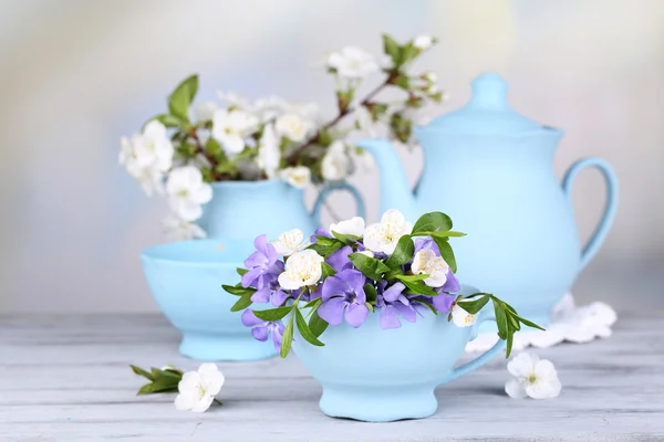 Schöne Frühlingsblumen in Tassen auf Holztisch — Stockfoto