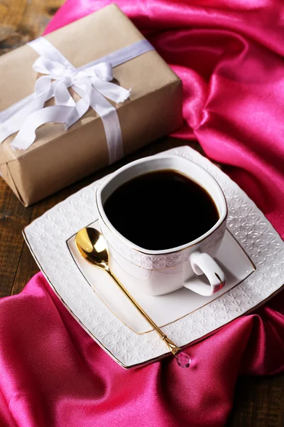 Tazza di caffè e regalo sul tavolo in legno primo piano — Foto Stock