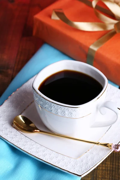 Cup of coffee and gift on wooden table close-up — Stock Photo, Image