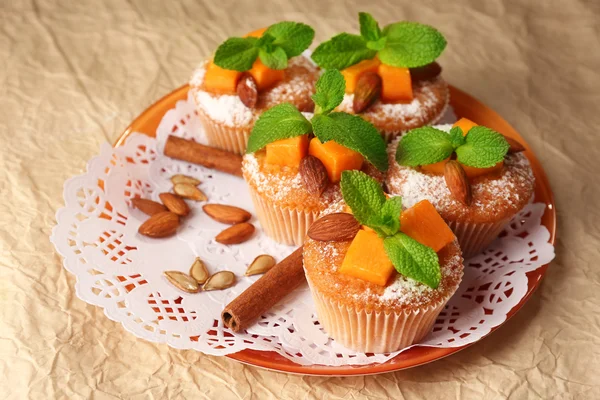 Tasty pumpkin muffins on brown paper — Stock Photo, Image