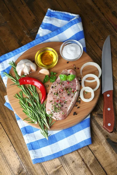 Raw meat steak with herbs and spices on cutting board, on wooden background — Stock Photo, Image