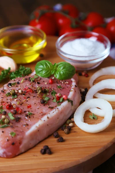 Nyers hús steak, gyógynövények és fűszerek, vágódeszka, fából készült háttér — Stock Fotó