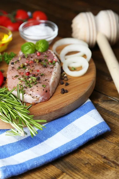 Steak de viande crue aux herbes et épices sur planche à découper, sur fond bois — Photo