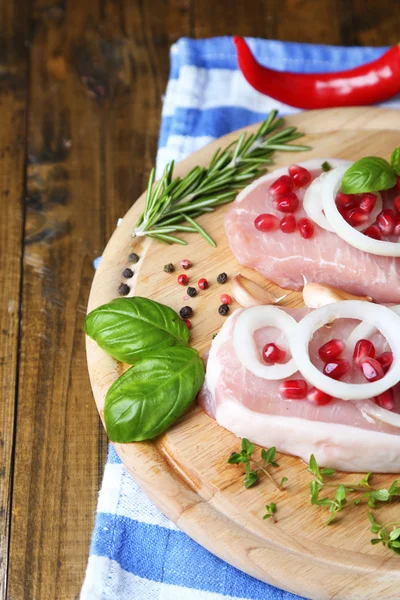 Bistecca di carne cruda con erbe e spezie sul tagliere, su fondo di legno — Foto Stock