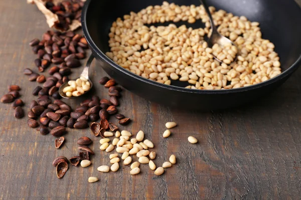 Cedar pine nuts on pan, on wooden table — Stock Photo, Image