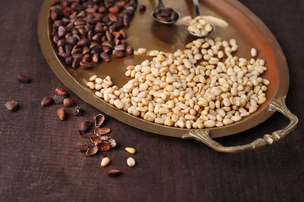 Cedar pine nuts on old metal tray, on wooden table — Stock Photo, Image