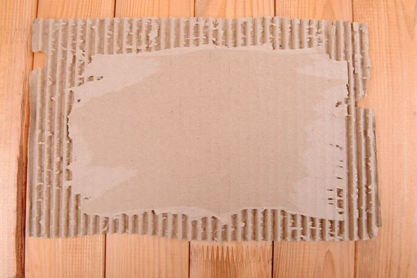 Cardboard on wooden background — Stock Photo, Image