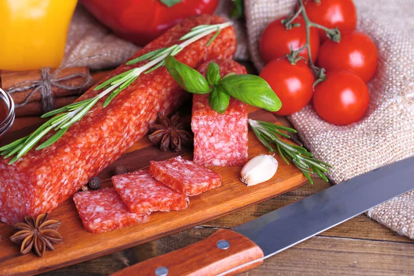 Sabrosa salchicha salami y especias sobre fondo de madera — Foto de Stock