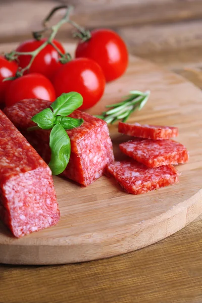 Tasty salami sausage and spices on wooden background — Stock Photo, Image