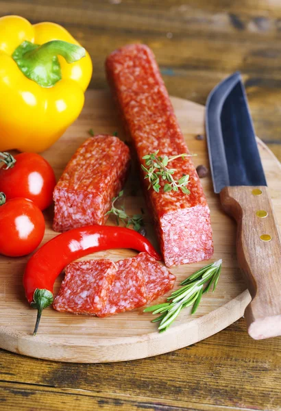 Leckere Salamiwurst und Gewürze auf Holzgrund — Stockfoto