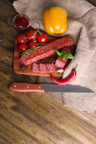 Salsicha de salame saboroso e especiarias em fundo de madeira — Fotografia de Stock