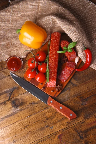 Salsicha de salame saboroso e especiarias em fundo de madeira — Fotografia de Stock