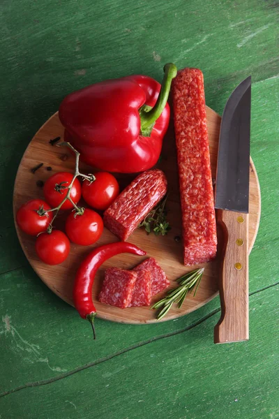 Leckere Salamiwurst und Gewürze auf Holzgrund — Stockfoto