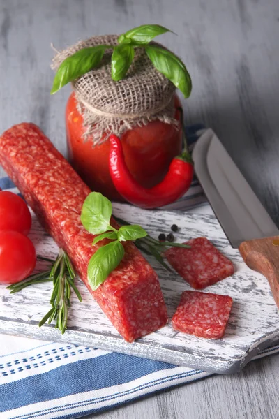 Sabrosa salchicha salami, verduras, cuchillo y especias sobre fondo de madera —  Fotos de Stock