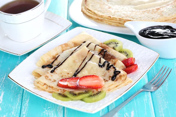 Deliciosas panquecas com morangos e chocolate no prato na mesa — Fotografia de Stock