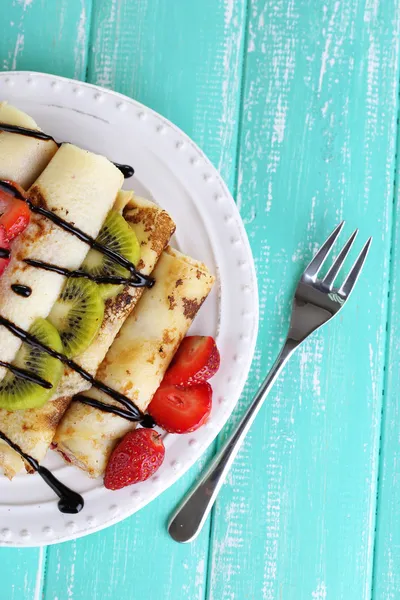 Deliziose frittelle con fragole e cioccolato sul piatto sul tavolo — Foto Stock