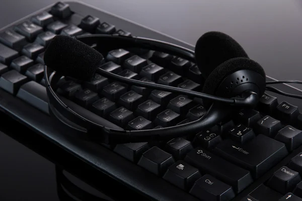 Auscultadores no teclado isolados em preto — Fotografia de Stock