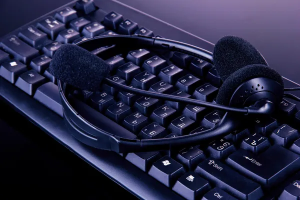 Headphones on keyboard isolated on black — Stock Photo, Image