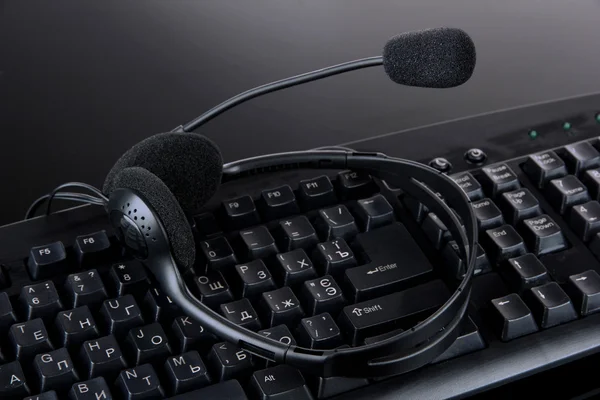 Headphones on keyboard isolated on black — Stock Photo, Image
