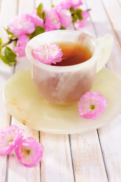 Beautiful fruit blossom with cup of tea on table close-up — Stock Photo, Image