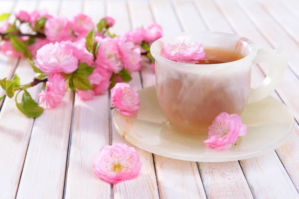 Beautiful fruit blossom with cup of tea on table close-up — Stock Photo, Image