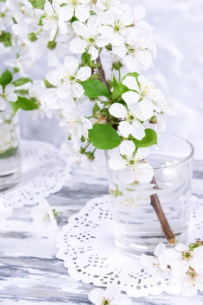 Schöne Obstblüte im Glas auf Tisch auf grauem Hintergrund — Stockfoto