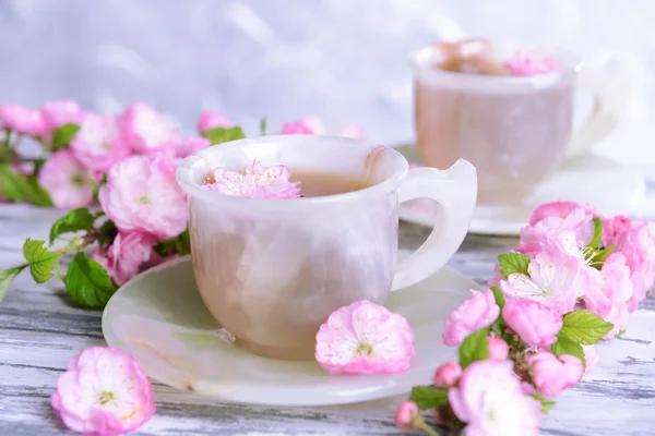 Hermosa flor de fruta con taza de té en la mesa sobre fondo gris —  Fotos de Stock