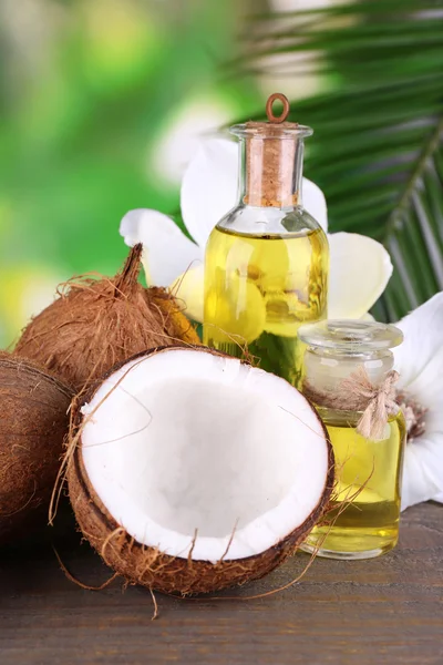 Orzechy kokosowe i olej kokosowy na drewnianym stole, na tle przyrody — Zdjęcie stockowe