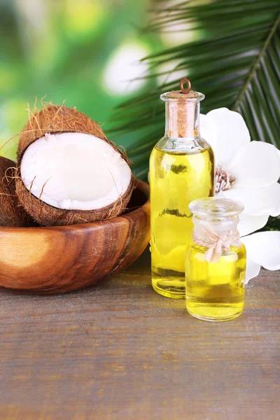 Coconuts and coconut oil on wooden table, on nature background — Stock Photo, Image