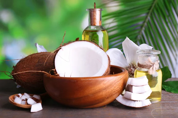 Coconuts and coconut oil on wooden table, on nature background — Stock Photo, Image