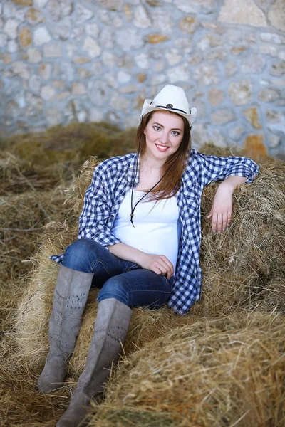 Beautiful cowgirl style model posing on farmland in hay — Stock Photo, Image