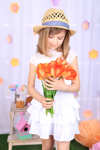 Hermosa niña sosteniendo flores sobre fondo decorativo — Foto de Stock