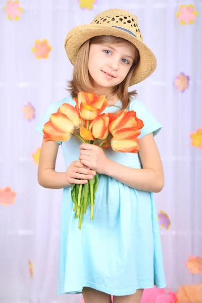 Vacker liten flicka med blommor på dekorativa bakgrund — Stockfoto