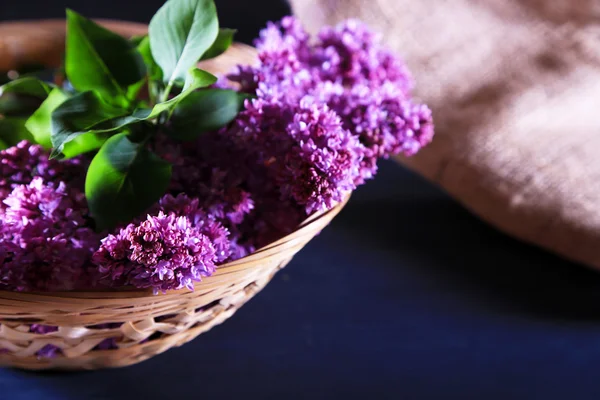 Bellissimi fiori lilla in cesto di vimini, su sfondo di legno a colori — Foto Stock