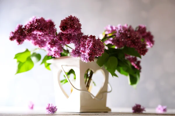 Lindas flores lilás em vaso, sobre mesa de madeira, sobre fundo de cor — Fotografia de Stock
