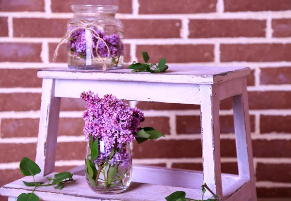 Lindas flores lilás em vasos, na escada de madeira, no fundo da parede de cor — Fotografia de Stock