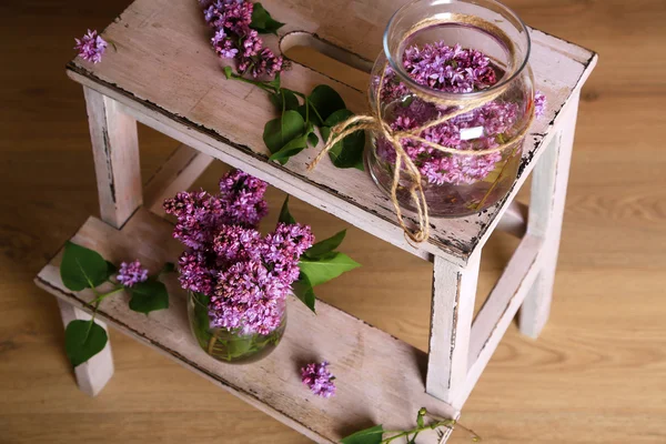 Lindas flores lilás em vasos, na escada de madeira, no fundo da parede de cor — Fotografia de Stock