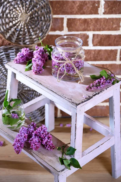 Lindas flores lilás em vaso, na escada de madeira, no fundo da parede de cor — Fotografia de Stock