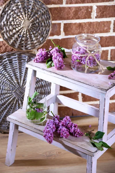 Lindas flores lilás em vaso, na escada de madeira, no fundo da parede de cor — Fotografia de Stock