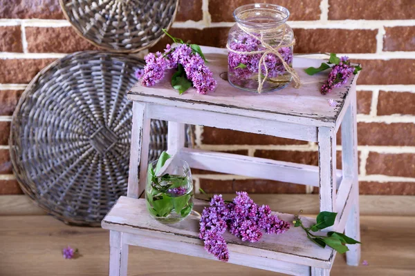 Lindas flores lilás em vaso, na escada de madeira, no fundo da parede de cor — Fotografia de Stock
