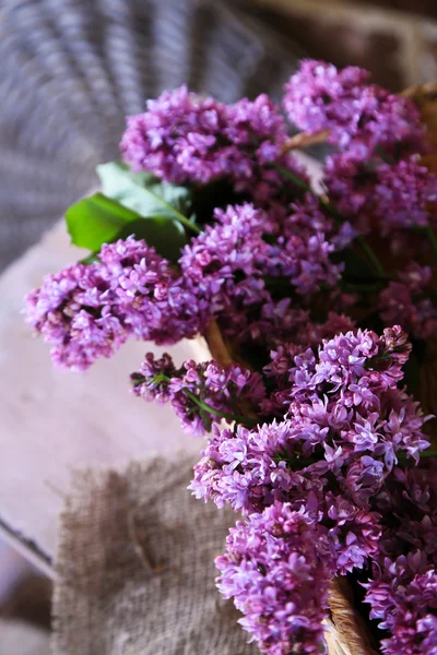Bellissimi fiori lilla in cesto di vimini su sfondo parete a colori — Foto Stock