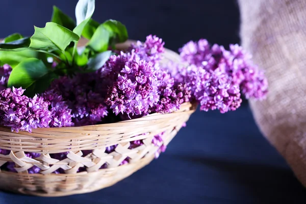 Bellissimi fiori lilla in cesto di vimini, su sfondo di legno a colori — Foto Stock